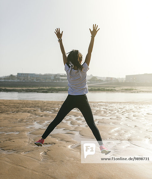 Spanien  Gijon  junge Frau beim Springen am Strand