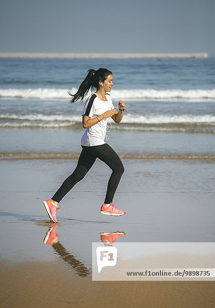 Spanien  Gijon  junge Frau  die am Strand läuft