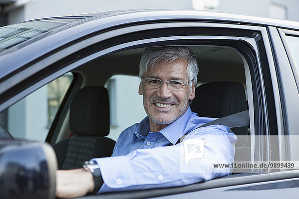 Portrait of smiling businessman sitting in his car