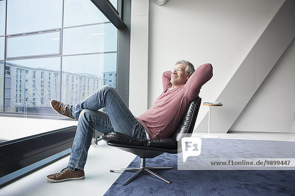 Mann entspannt in einem Ledersessel zu Hause