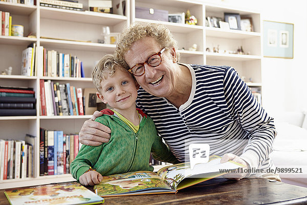 Grandfather and grandson reading children's book together