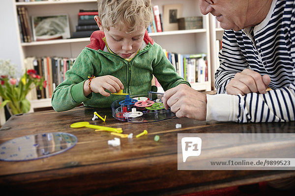 Großvater und Enkel montieren Spielzeuguhr