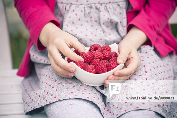 Girl with raspberries in a bowl