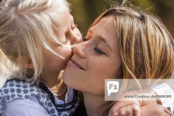 Mädchen umarmend und küssend lächelnde Mutter