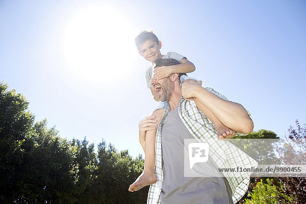Vater trägt Sohn auf Schultern  spielt im Garten