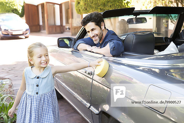 Father and daughter polishing convertible