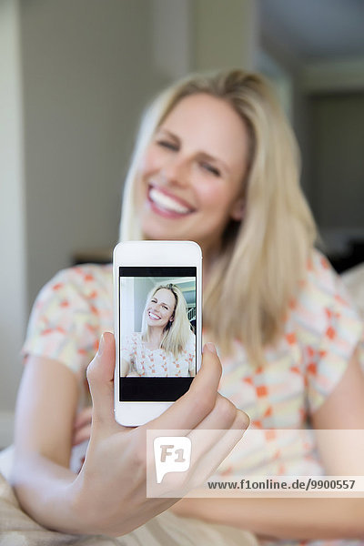 Blonde Frau nimmt Selfie mit Smartphone
