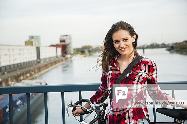 Deutschland  Mannheim  junge Frau mit Fahrrad auf Brücke