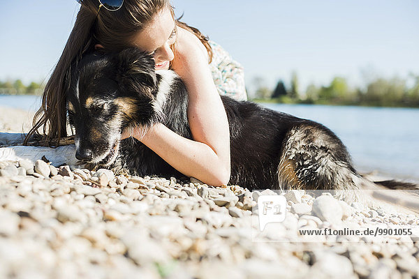 Deutschland,  Mannheim,  junge Frau kuschelt mit Hund am Rhein