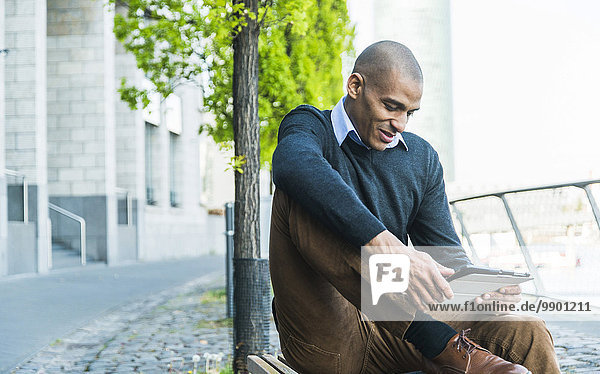 Mann auf der Bank sitzend mit digitalem Tablett