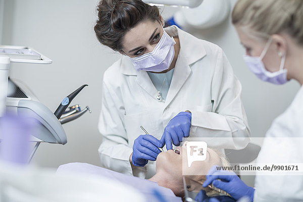 Zahnärztin untersucht Patientin mit Mundspiegel