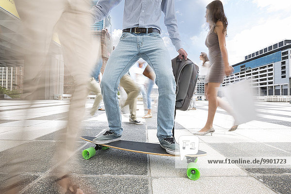 Stadtpendler auf einem Skateboard zwischen einer Menschenmenge