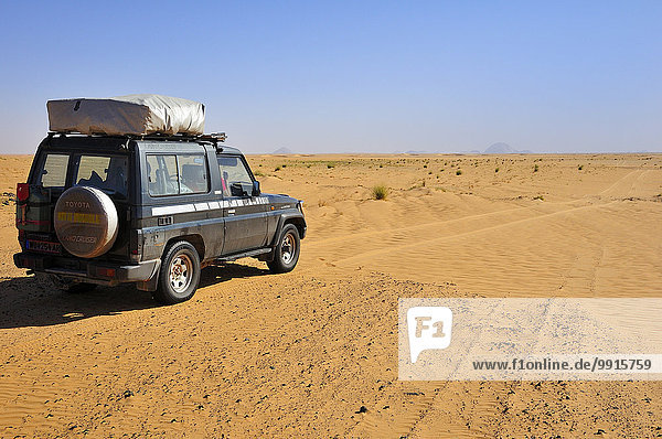 Geländefahrzeug mit Dachzelt auf der Piste  hinten der Monolith Aicha  Region Adrar  Mauretanien  Afrika