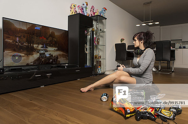 Junge Frau beim Gamen mit Playstation im Wohnzimmer