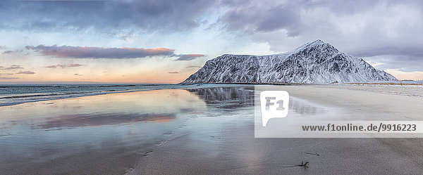Ein Berg spiegelt sich im Wasser des Ozeans am Strand von Skagsanden  Lofoten  Norwegen  Europa