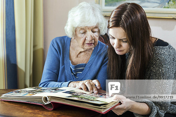 Großmutter und Enkelin beim Betrachten des Fotoalbums im Haus