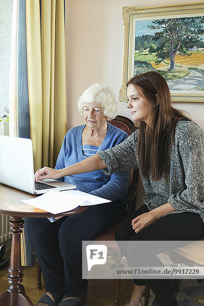 Großmutter und Enkelin nutzen gemeinsam den Laptop zu Hause