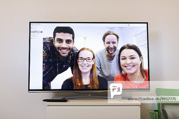Glückliche Geschäftsleute auf dem Bildschirm im Videokonferenzraum des Kreativbüros