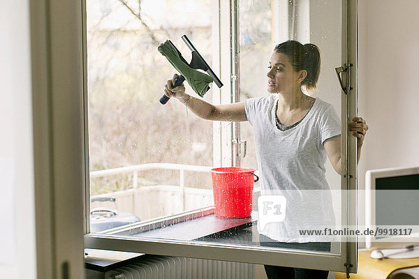 Frau reinigt Glasfenster