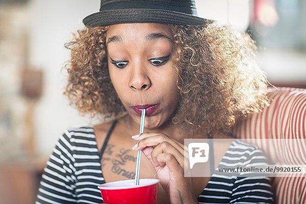 Porträt einer jungen Frau  die beim Trinken von Erfrischungsgetränken ein Gesicht zieht.