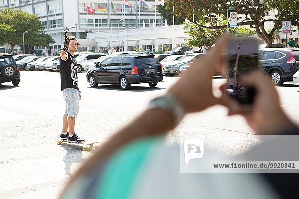 Father taking smartphone photograph of son skateboarding  Copacabana  Rio De Janeiro  Brazil