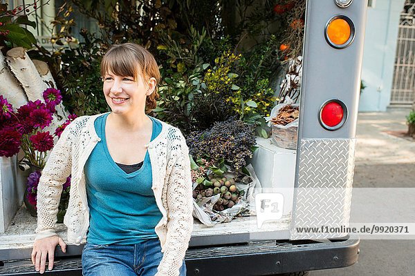 Portrait of florist sitting on back of delivery truck