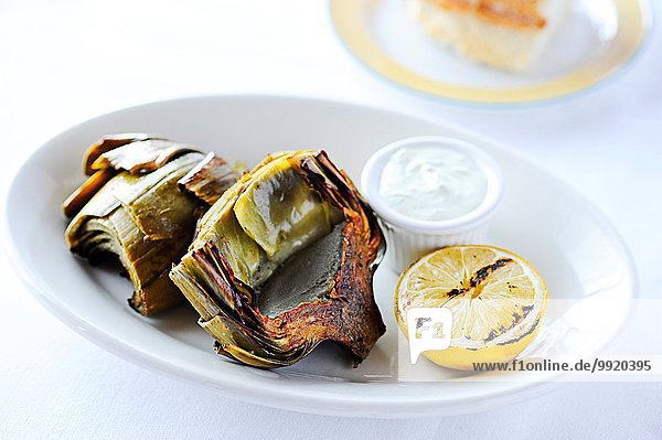 Grilled artichokes with lemon on restaurant table