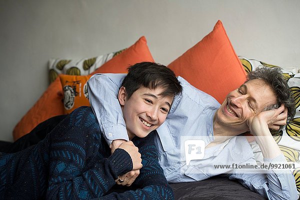 Portrait of teenage boy and father reclining on sofa