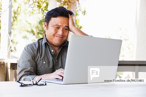 Frustriert reifen Geschäftsmann arbeiten auf dem Laptop in der Veranda
