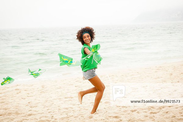Junge Frau spielt mit Fahnenkette am Strand  Rio de Janeiro  Brasilien