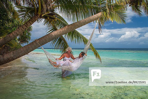 Senior Mann in der Hängematte mit Frau  Malediven