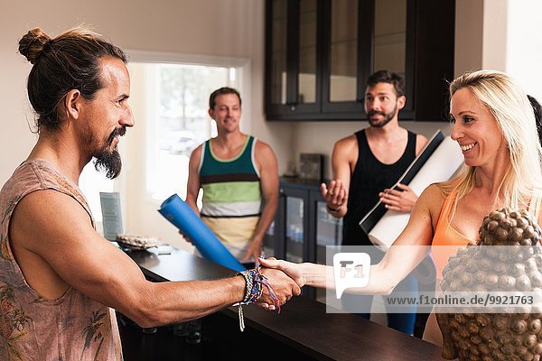 Mid adult woman shaking hands with yoga instructor