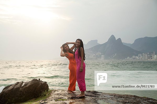 Portrait of two young women standing on rock  Ipanema beach  Rio De Janeiro  Brazil