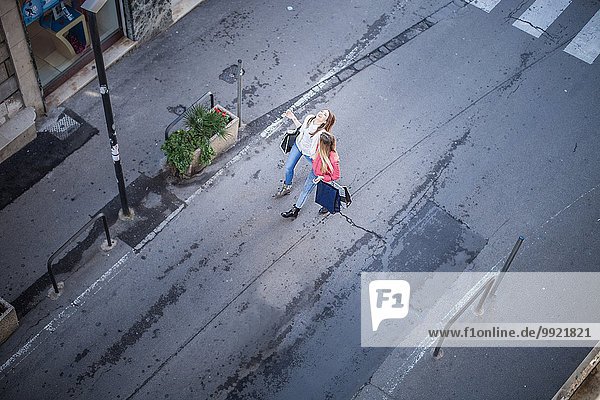 Blick von zwei Freundinnen  die beim Spazierengehen auf der Stadtstraße lachen.