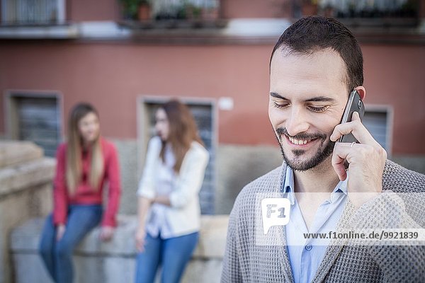 Mann mit Freundinnen im Gespräch auf Smartphone  Cagliari  Sardinien  Italien