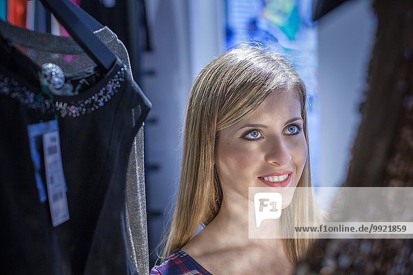 Young woman admiring dress in boutique