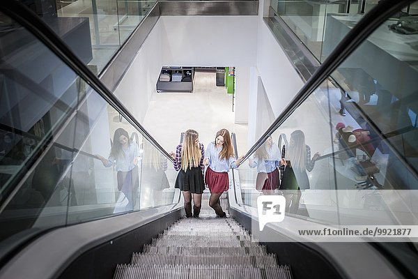 Zwei Freundinnen auf der Rolltreppe im Einkaufszentrum