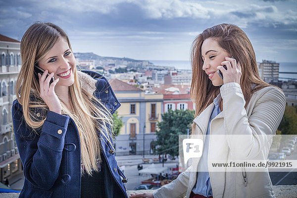 Zwei junge Frauen auf dem Dach sprechen auf Smartphones  Cagliari  Sardinien  Italien