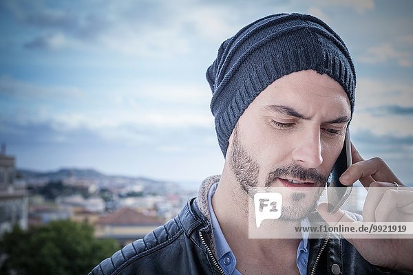 Nahaufnahme eines Mannes auf dem Dach  der auf dem Smartphone spricht  Cagliari  Sardinien  Italien