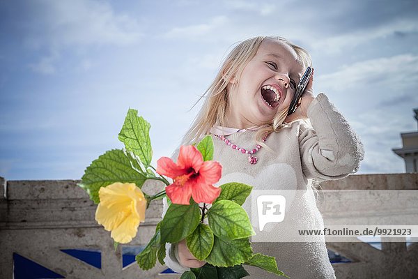 Junges Mädchen mit Blumen lachend und plaudernd auf Smartphone  Cagliari  Sardinien  Italien