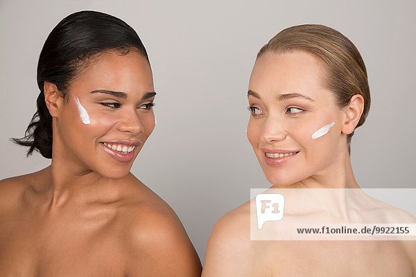 Portrait von zwei jungen Frauen mit Schönheitscreme im Gesicht