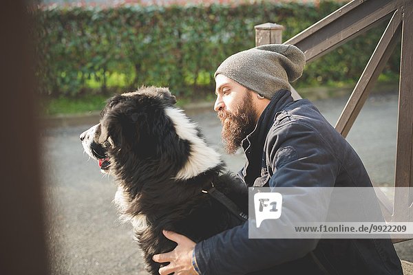 Mittlerer Erwachsener Mann sitzend mit Hund  im Freien