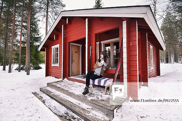 Portrait einer jungen Skifahrerin beim Kaffeetrinken auf der Veranda  Posio  Lappland  Finnland