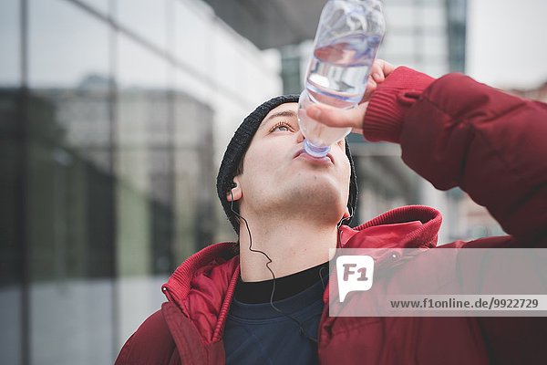 Junger Mann trinkt Wasser vor dem Stadtbüro