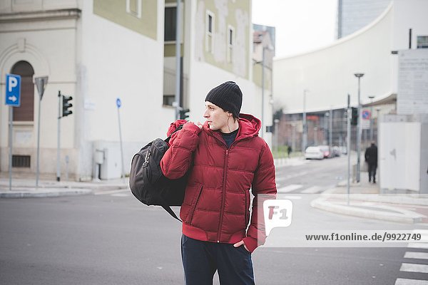 Junger Mann mit Koffer auf der Stadtstraße