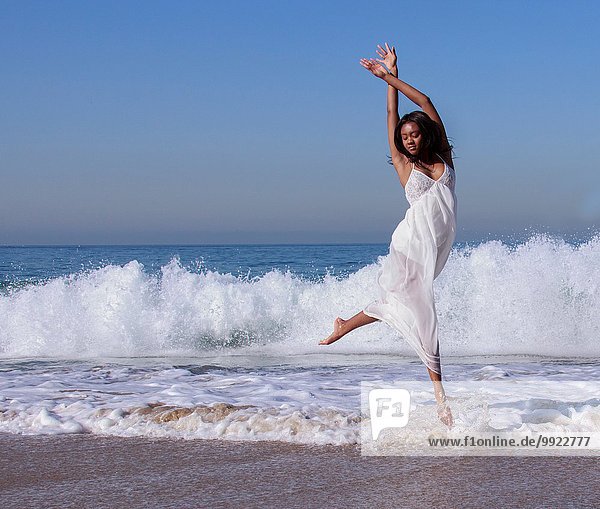 Junge Tänzerin springt in der Luft in Meereswellen