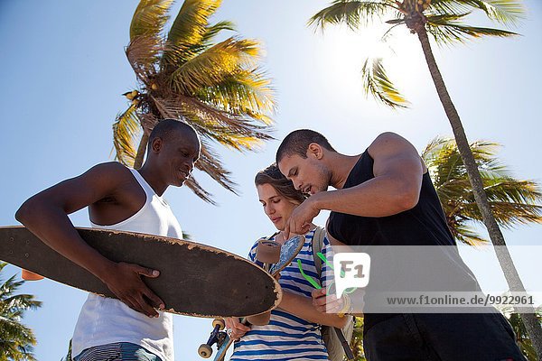 Young man holding skateboard with friends low angle