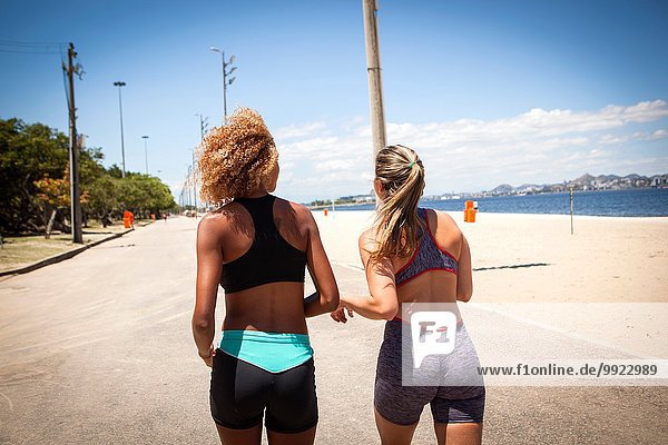 Two young women jogging on beach  rear view