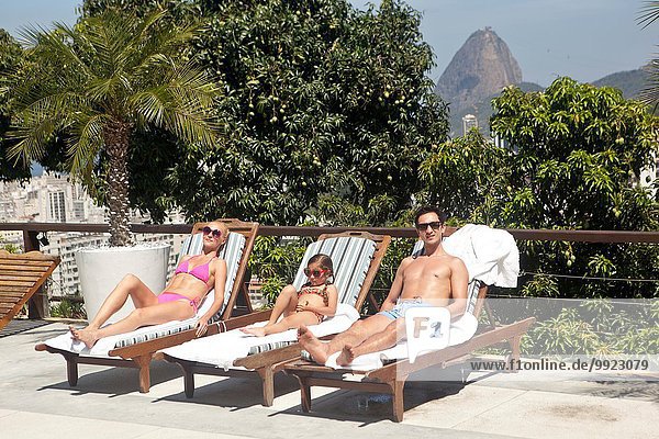 Young family sunbathing by pool  Rio de Janeiro  Brazil