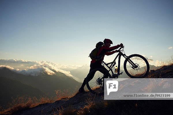 Mountainbiker schieben Fahrrad bergauf  Wallis  Schweiz